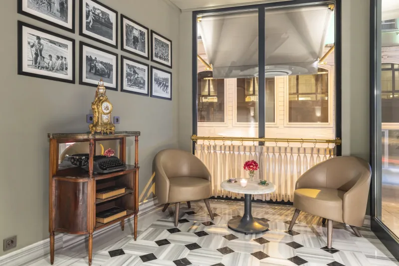 Un angolo della hall dell'Hotel Marius, con una parete di fotografie incorniciate e un mobile d'epoca