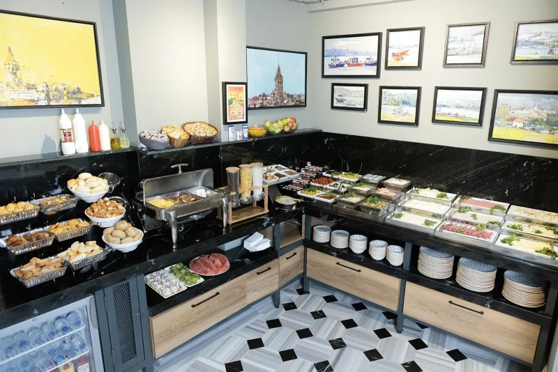 L'angolo buffet dell'Hotel Marius, con piatti caldi, stoviglie e quadri incorniciati