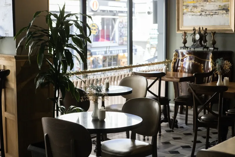 Un tavolo accanto alla finestra nella sala colazioni dell'Hotel Marius, vicino a un samovar di rame