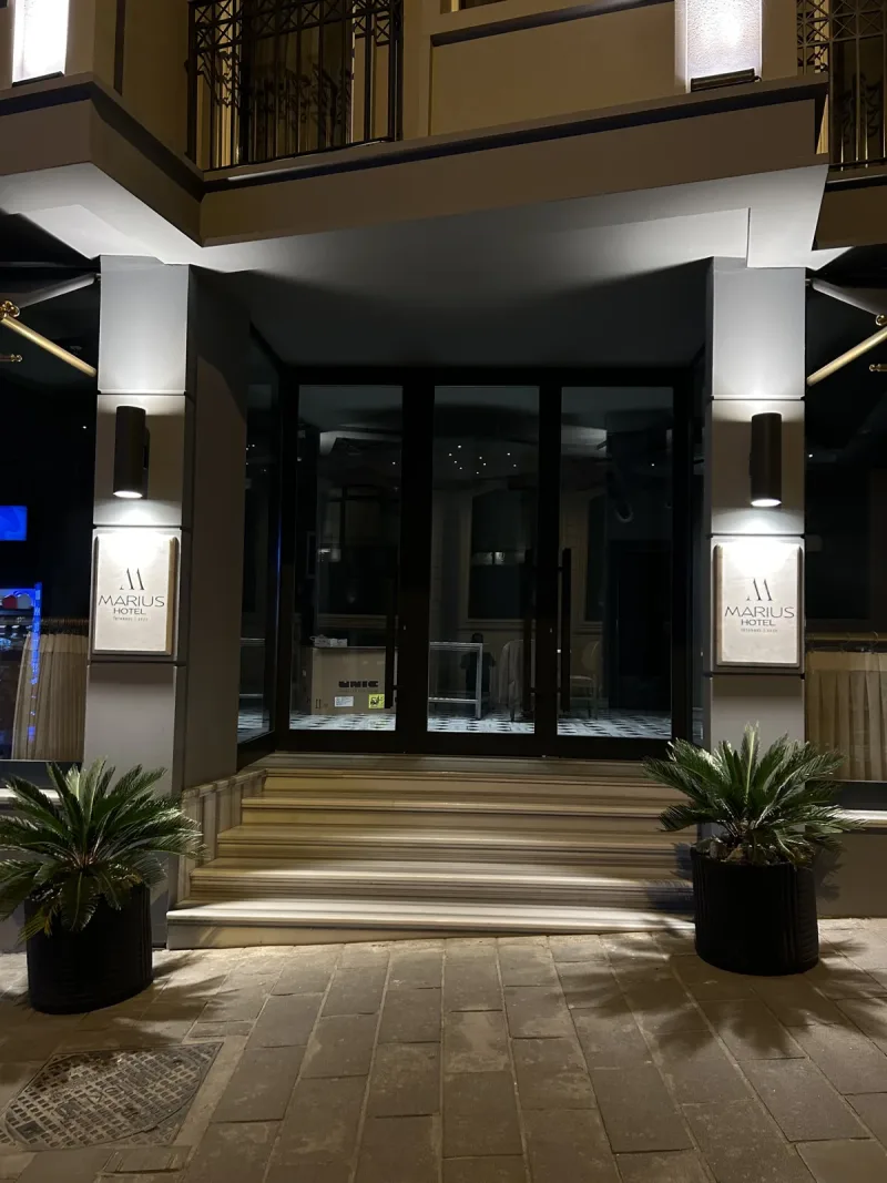 The entrance of Hotel Marius lit up at night, with its steps and palms
